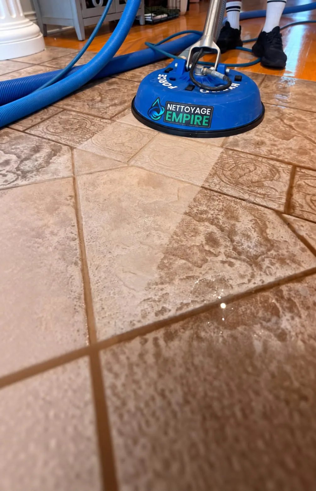 Machine bleue Nettoyage Empire montrant le contraste avant-après sur un plancher de tuiles de céramique encrassé
